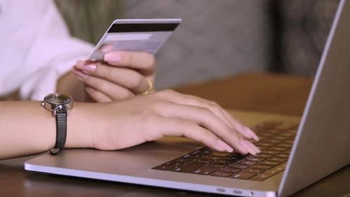Mädchen halten Kreditkarte in Händen und benutzen Laptop