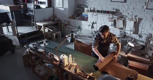 Man Unrolling Leather in Workshop