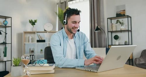 Joven con auriculares que disfruta de una videoconferencia con amigos en una computadora portátil en casa durante el día