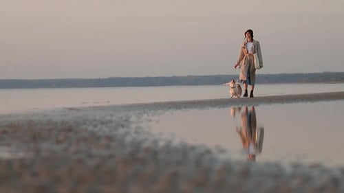Dog and Woman Walking Along Beach in Background of Water Spbi