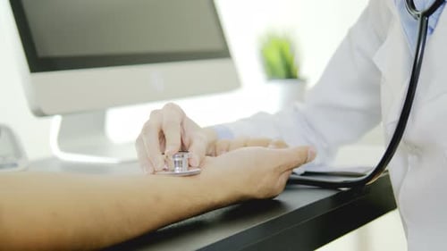 Arzt hört auf das Handgelenk des Patienten