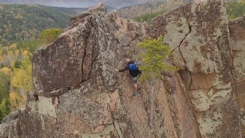 Adult Scaling Steep Cliff Face in Nature Setting