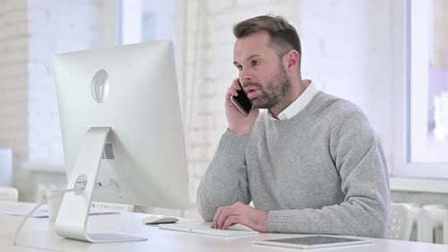 Kreativer Mann spricht bei der Arbeit auf dem Smartphone