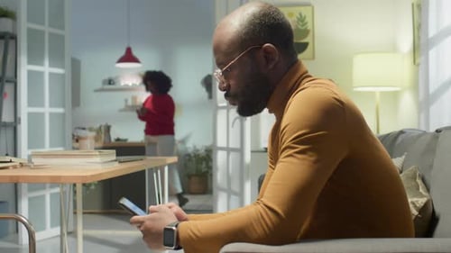 Man Using Smartphone on Couch at Home