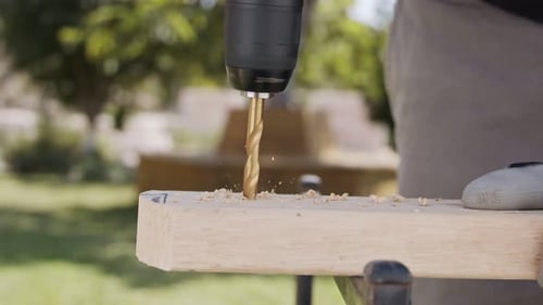 Close up of a drill making a hole in a piece of wood - slow motion
