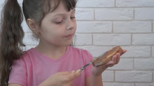 Cute Girl Spreads Jam on Toast at Home