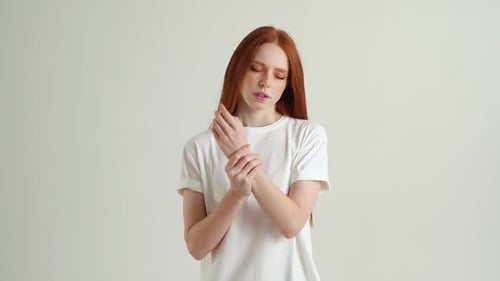 Retrato de una joven frustrada con una mueca de dolor masajeando una muñeca dolorida que sufre una lesión en la mano o