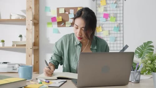 Young Woman Teleconferencing While Taking Notes