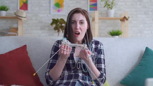 Frustrated Woman with Tangled Yarn on Couch