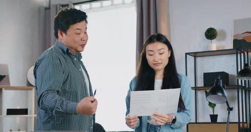Two Young Adults Collaborating on Documents Indoors