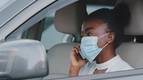 Woman with Face Mask Talking on Mobile Phone in Car