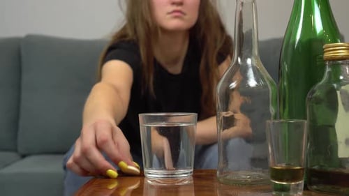 Young Adult Drops Tablet into Water Near Alcohol
