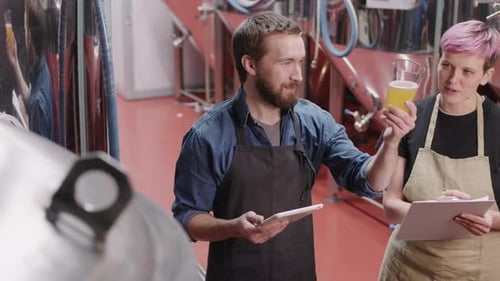 Brewery Workers Checking Beer Sample At Factory