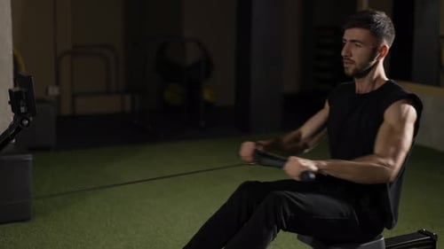Bearded Sportsman Works Out in Gym with Rowing Machine