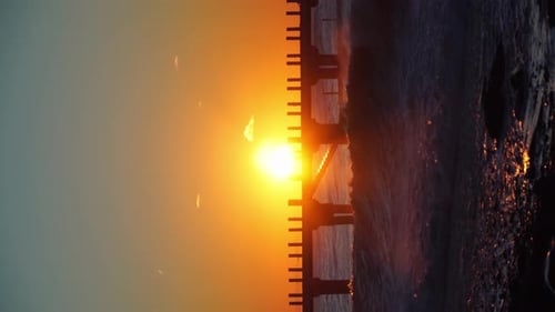 Bei Sonnenuntergang treffen heiße Sturmwellen auf den Pier. Wunderschöner oranger Himmel, krachende Wellen
.