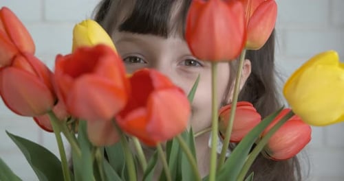 Child with Flowers Bouquet Peeking Through Tulips