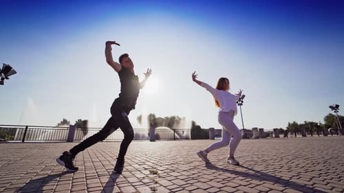 Dancing couple in the city. Outdoor view of young beautiful fashionable couple dancing