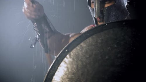 Muscular Man in Helmet Holds Spear in the Rain