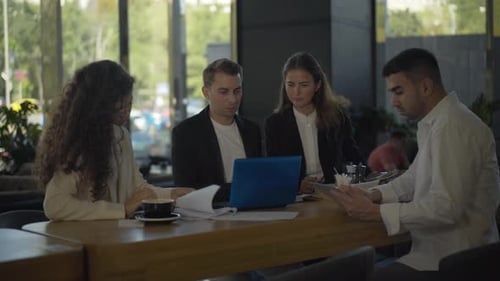 Four Multiethnic Young People Having Business Lunch in Cafe. Portrait of Busy Confident Caucasian