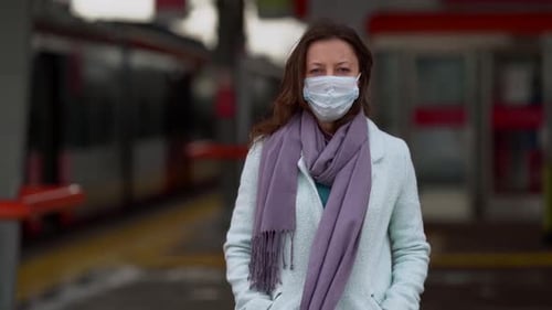 Woman Passenger with Face Mask Is Walking Over Open Platform of Train Station, Cold Windy Autumn Day