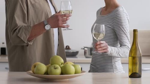 Couple Cheers White Wine in Bright Kitchen