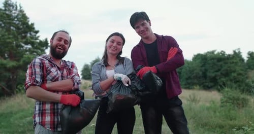 Young Adults Volunteering Holding Trash Bags in Field