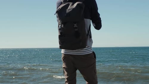 Man Traveler with Backpack Relaxing Outdoor Sea and Rocks Coastal on Background Freedom Lifestyle