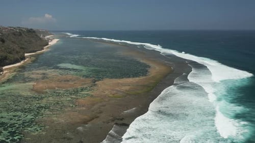 Aerial drone view of waves and surf breaking onto a tropical reef