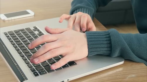 Hands Typing on Laptop Keyboard in Office