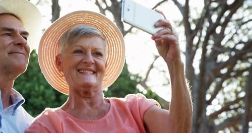 Senior couple taking selfie form mobile phone in park