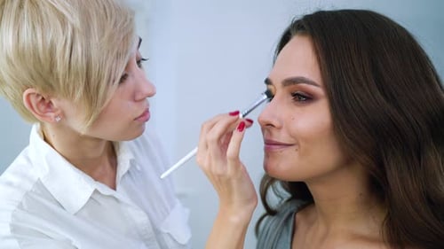 Makeup Artist Applying Eye Shadow to Beautiful Woman
