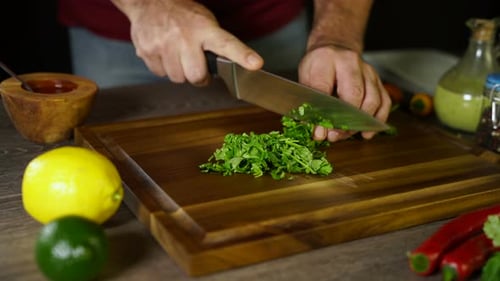Person Chopping Greens on Wooden Cutting Board