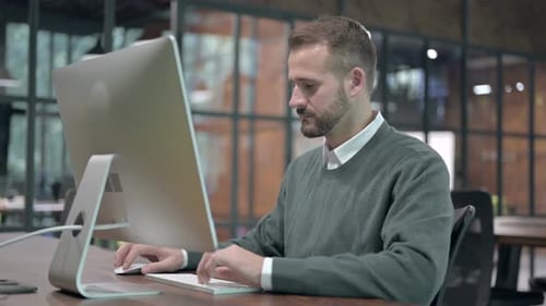 Smiling Man Using Computer in Modern Office