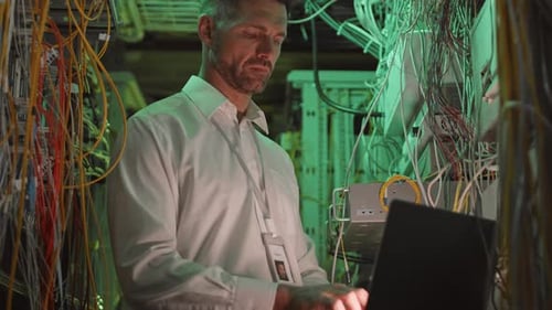 Man Working on Laptop in Server Room