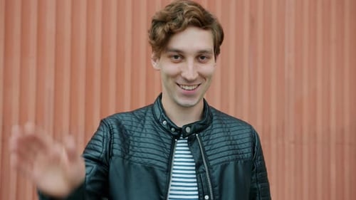 Young Adult Waving in Front of Orange Wall