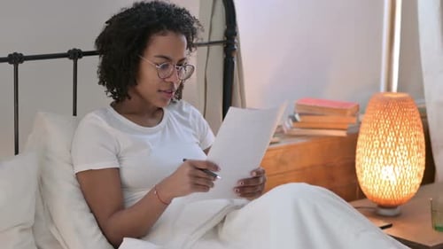 Young Woman Reading and Making Notes in Bed