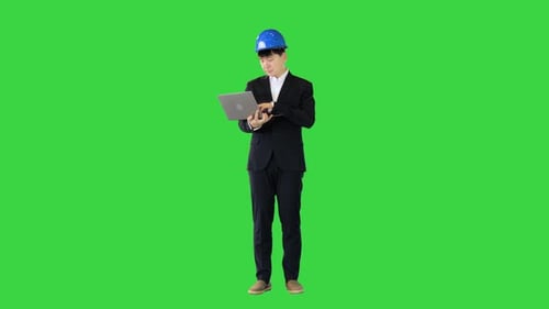 Engineer in a Suit Standing and Working on a Laptop on a Green Screen Chroma Key