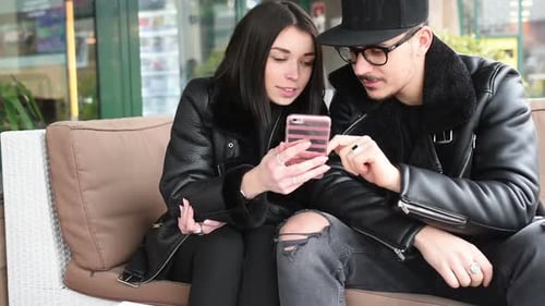 Joven y hermosa pareja al aire libre en la ciudad usando un teléfono inteligente