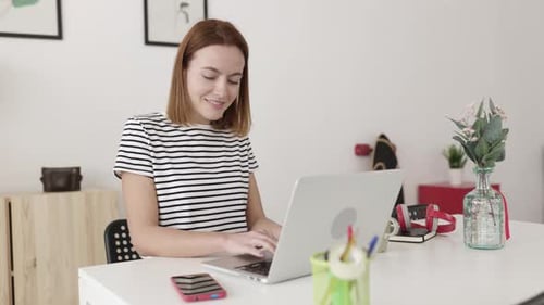 Woman Using Laptop at Desk in Bright Home Office