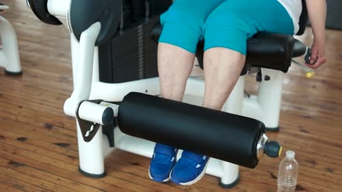 Feche as pernas femininas na máquina de levantamento de peso.