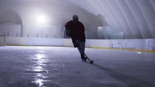 Hockey Player Skating and Maneuvering Puck on Ice