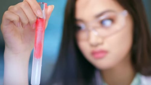 Young Scientist Inspecting Red Liquid in Test Tube