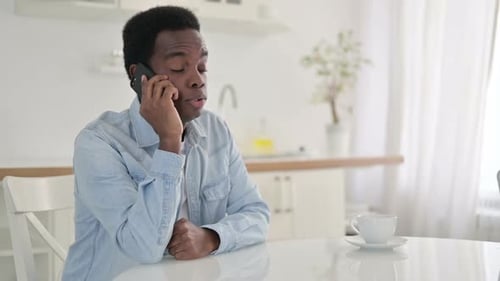 Young Adult Chatting on Mobile Phone in Kitchen