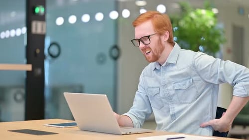 Casual Redhead Man with Laptop Having Back Pain in Office