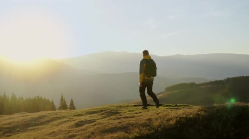 Man Walks to Hilltop Overlooking Mountain Landscape at Sunrise