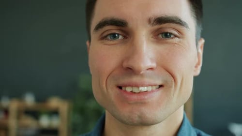 Nahaufnahme Porträt eines attraktiven jungen Mannes, der im Haus lächelt und in die Kamera schaut