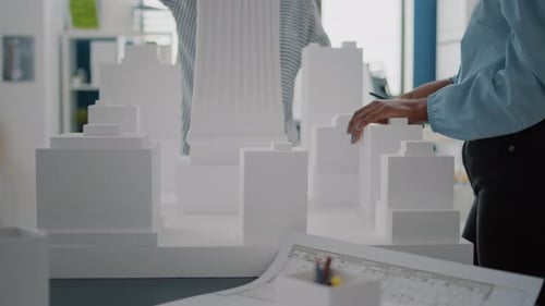 Close Up of Women with Building Model and Blueprints Plan on Table