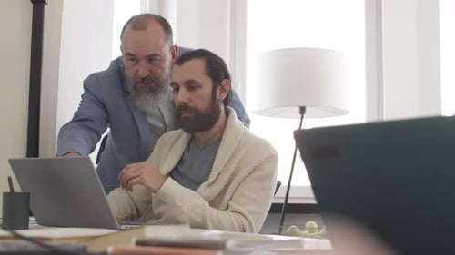 Men Collaborate on Laptop in Office