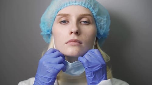 Woman Putting on Surgical Face Mask for Protection Against Coronavirus SARSCoV2