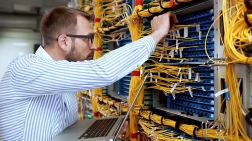 Man Working on Laptop In Front of Server